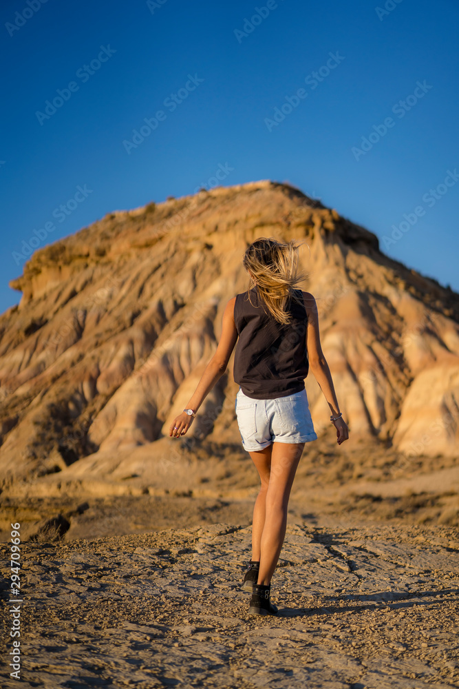Lifestyle of a young blonde with rocker look with high shoes walking towards a hill