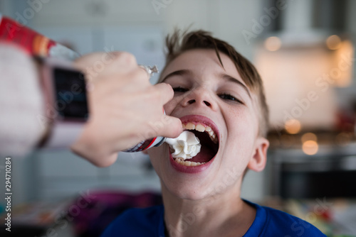 Whipped cream being sprayed into boy's mouth