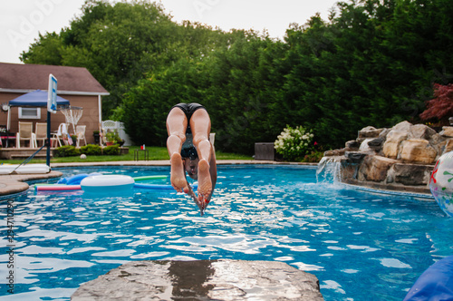 Girl diving off rock into pool photo