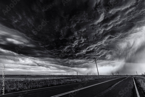 Heavy storm and cloud sky over road and farm fields, black and white