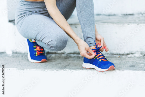 Attractive sportswoman tying shoelace and getting ready for fitness. Young woman runner tying shoelaces with copy space, healthy lifestyle and sport concepts. © avdeyukphoto
