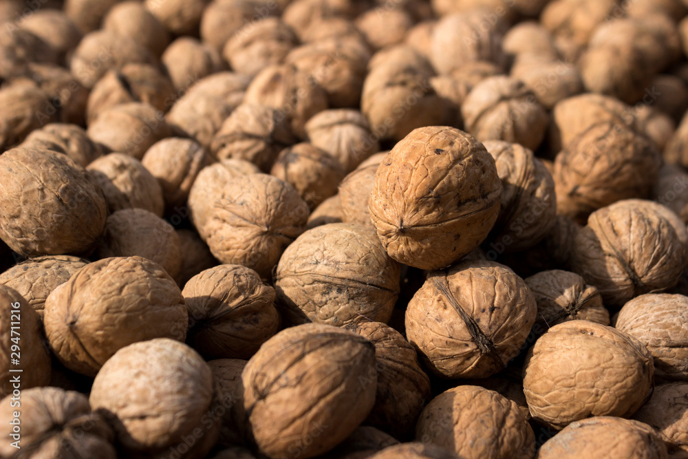 Inshell walnuts dried in the sun, background. Harvesting. Juglans regia, the Persian walnut, English walnut, Carpathian walnut, Madeira walnut common walnut Inshell walnuts dried in the sun, background. Harvesting. Juglans regia, the Persian walnut, English walnut, Carpathian walnut, Madeira walnut common walnut