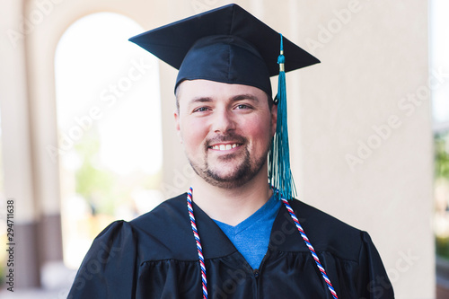 Smiling portrait of male graduate in black cap and gown photo