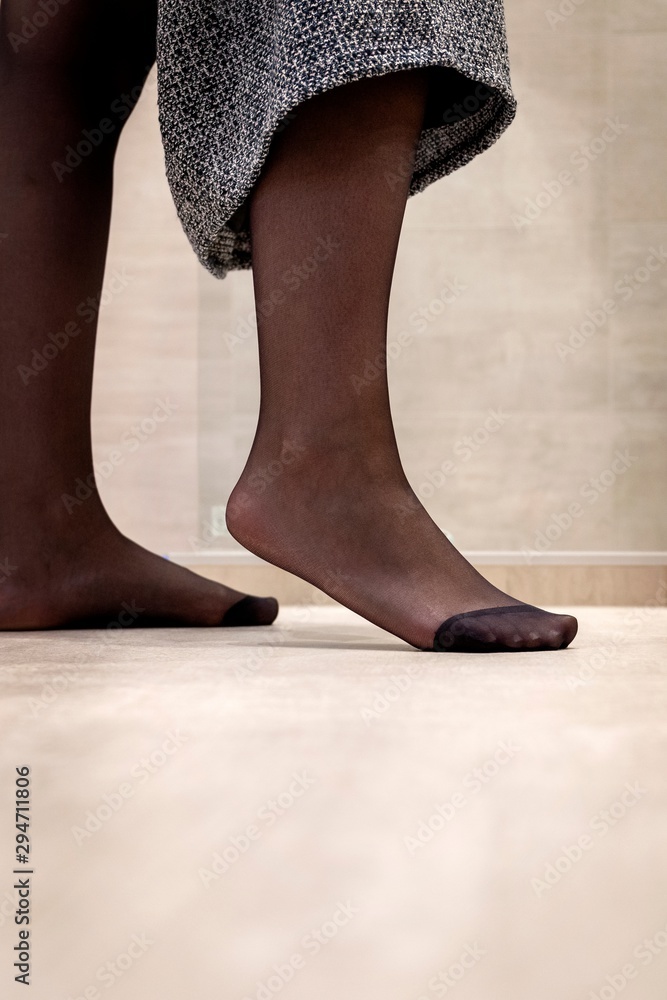 A close up portrait of a foot standing on the tip in black pantyhose of a  girl pulling up her skirt. The nylon is reinforced at the toes. Photos |  Adobe Stock