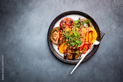 Foto Fresh colorful tomatoes salad with balsamic vinegar on a plate, top view
