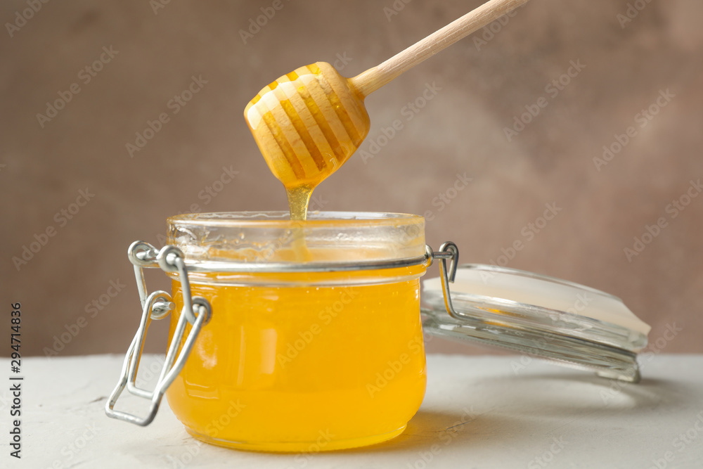 Glass jar with honey and dipper on white background, close up Glass jar with honey and dipper on white background, close up