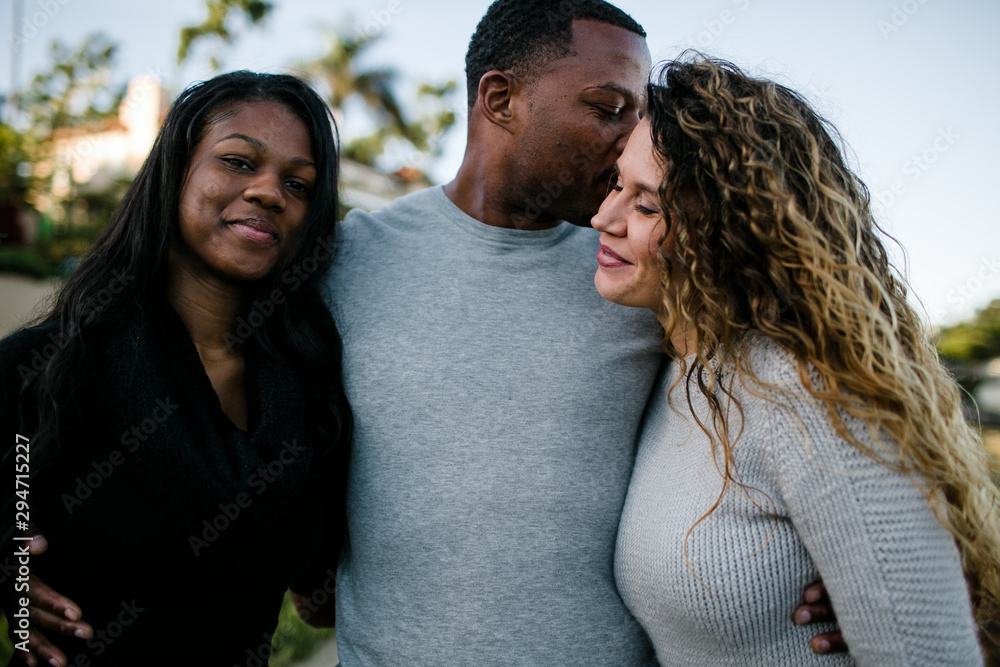 Husband kissing wife as daughter smiles on beach at sunset Husband kissing wife as daughter smiles on beach at sunset