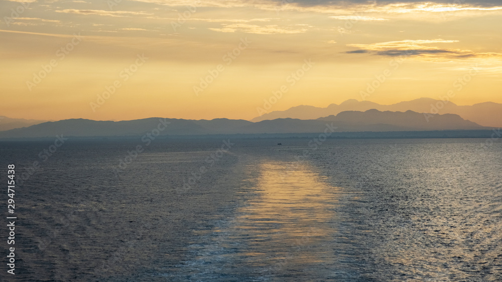 Nature in twilight period which including of sunrise over the blue water in the morning. Beautiful colorful landscape with boats, sea and purple sky. Golden light go through the cloud to the mountain Nature in twilight period which including of sunrise over the blue water in the morning. Beautiful colorful landscape with boats, sea and purple sky. Golden light go through the cloud to the mountain