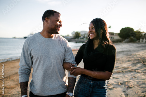 Father and daughter smiling at one another on beach at sunset