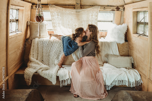 Mother and daughter kissing in boho studio setup photo