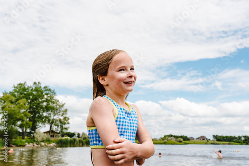 Little girl takes swim break on shore of lake during summer