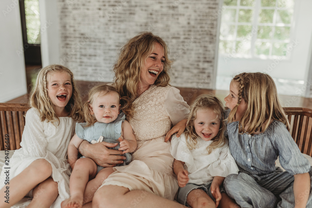 Mother and daughters looking at each other lovingly on studio couch Mother and daughters looking at each other lovingly on studio couch