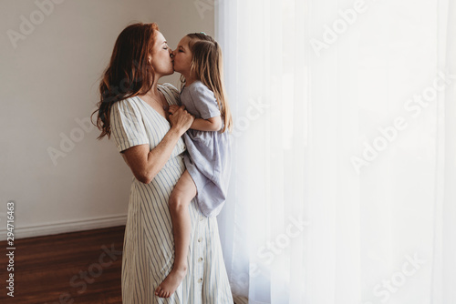Side view of young mother holding daughter and kissing in studio