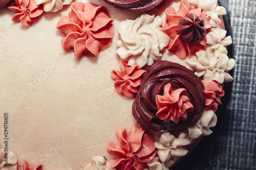 Pink cake with cream flowers on a dark background