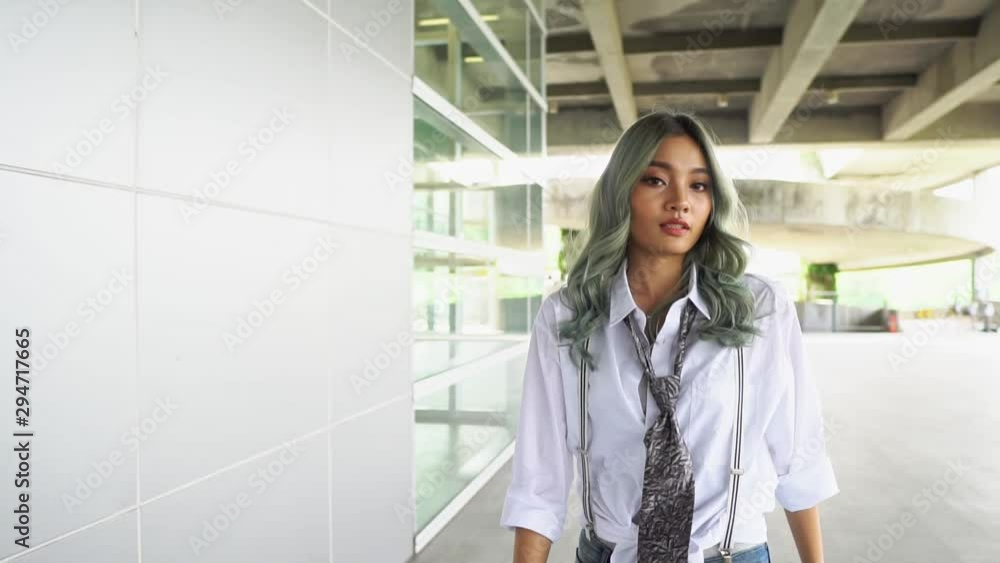 Asian Teenager girl turns around and looks at camera. Beautiful woman has long Green curl hair. Attractive fashion model is walking, shaking and flying curly green coloring hair. Slow Motion Gimbal Asian Teenager girl turns around and looks at camera. Beautiful woman has long Green curl hair. Attractive fashion model is walking, shaking and flying curly green coloring hair. Slow Motion Gimbal