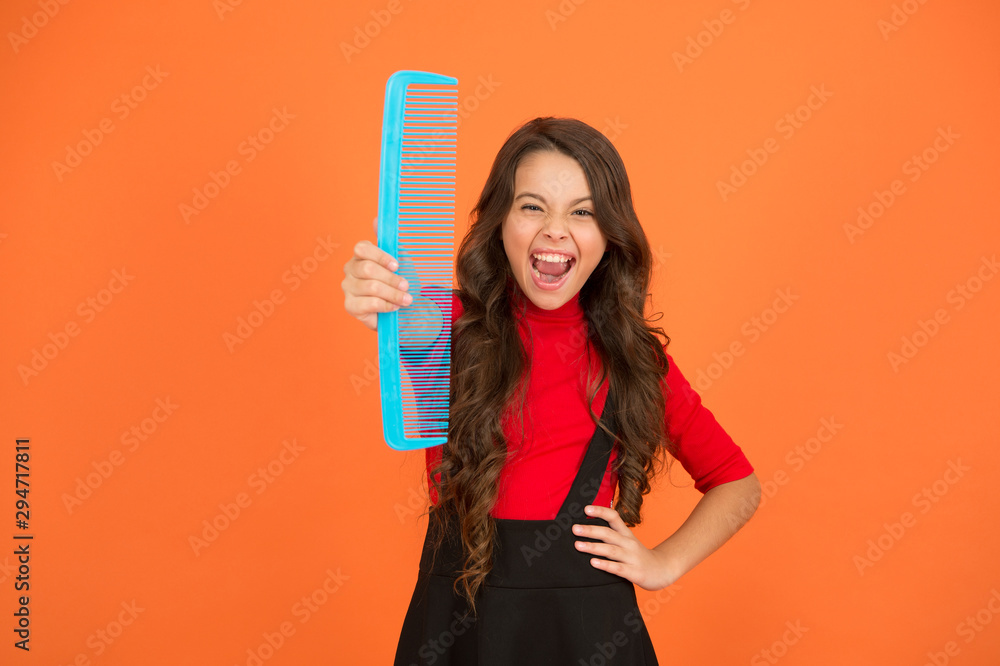 Get rid of annoying tangles. Large comb. Girl long hair hold enormous comb close up. Hairdresser salon. Combing hair. Cheerful smiling little kid with giant comb. Styling tips. Comb for tangled hair Get rid of annoying tangles. Large comb. Girl long hair hold enormous comb close up. Hairdresser salon. Combing hair. Cheerful smiling little kid with giant comb. Styling tips. Comb for tangled hair