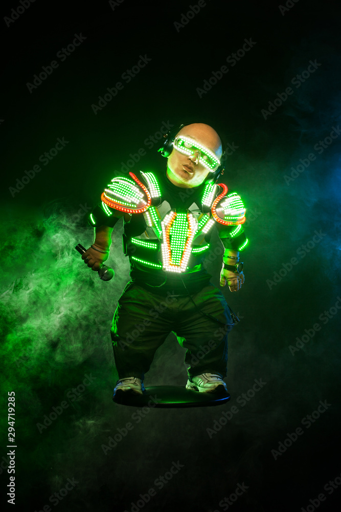 Little man, dwarf. Mysterious midget in black wear, neon mask and gloves. Character pastor assassin or wizard in robe from the future. Fantasy book or computer game cover concept.