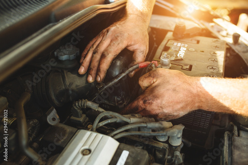 Close-up of mechanic repairing a car without gloves.