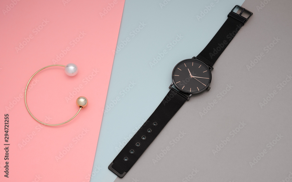 black wristwatch and golden pearl bracelet on pastel colors background black wristwatch and golden pearl bracelet on pastel colors background