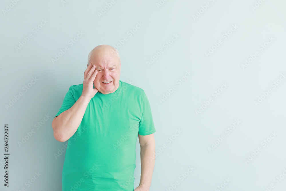 Senior man suffering from headache on light background Senior man suffering from headache on light background
