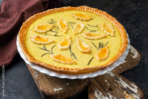 Traditional French Autumn pumpkin tarte offered as closeup in a backing form on an old wooden cutting board
