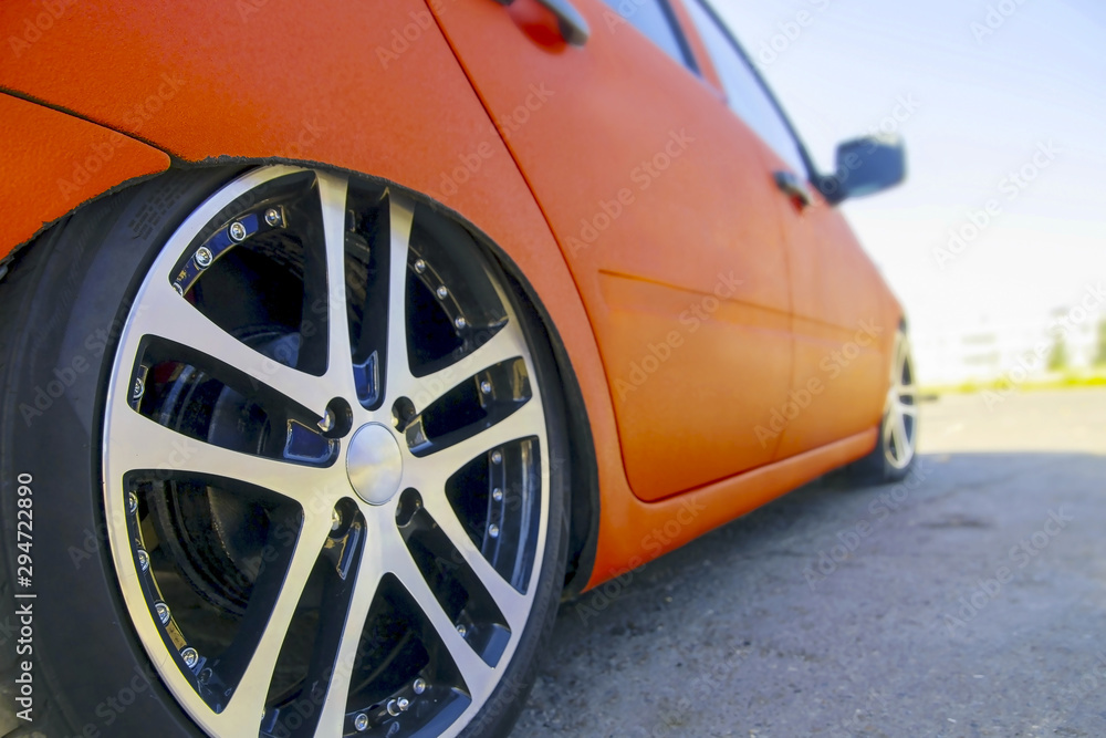 stylish beautiful chrome cast wheel rim on bright orange car