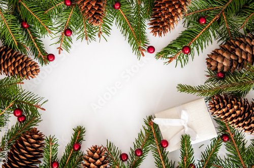 Christmas holiday picture in red and green colors, gift box, cones, green spruce branches, red balls, berries