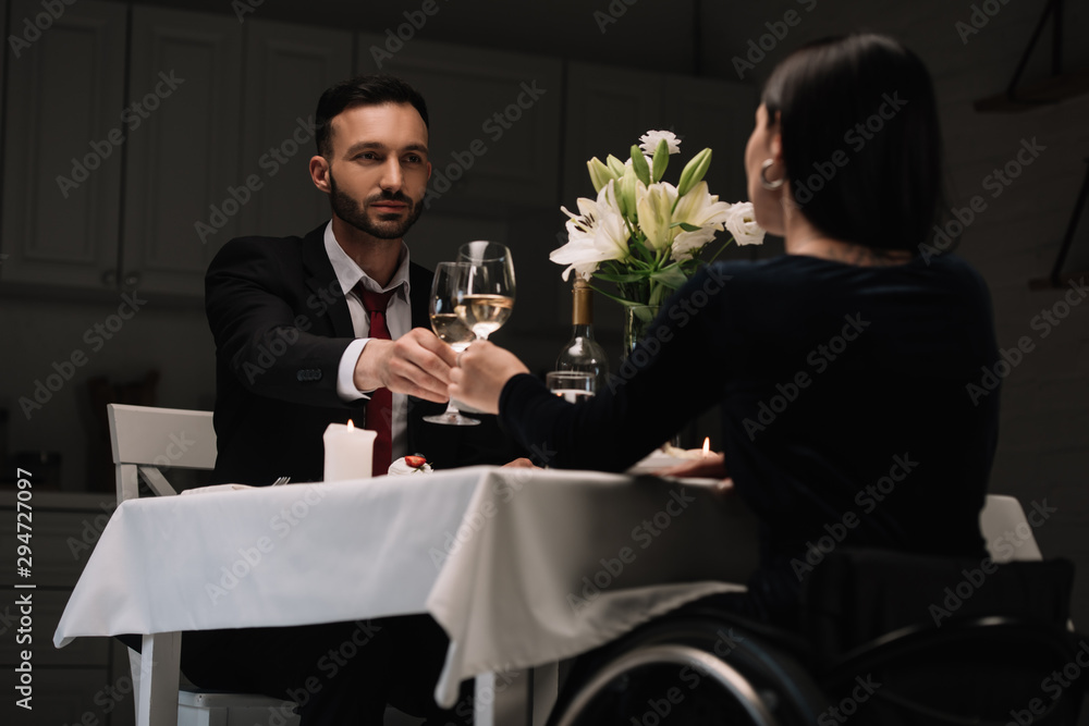 back view of disabled young woman clinking glasses of red wine with handsome boyfriend during romantic dinner back view of disabled young woman clinking glasses of red wine with handsome boyfriend during romantic dinner