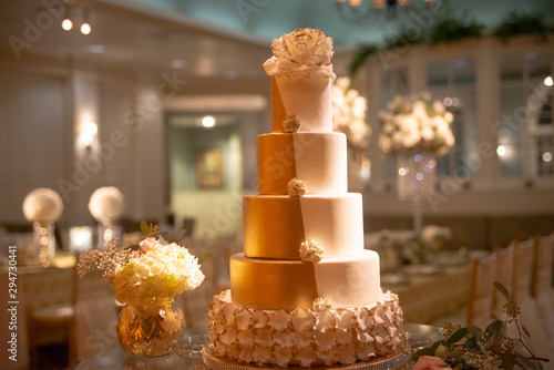Five tier white and gold tuxedo wedding cake with fondant lace on caake stand