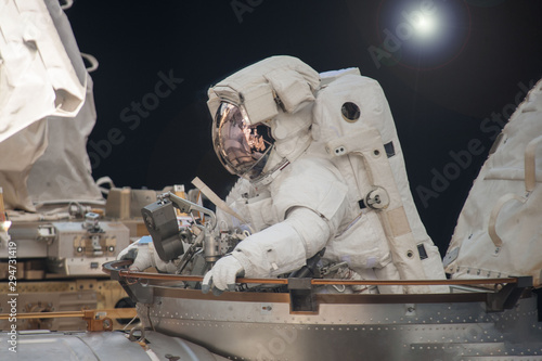 Astronaut in a spacesuit. At the space station. Engaged in maintenance. Elements of this image were furnished by NASA.