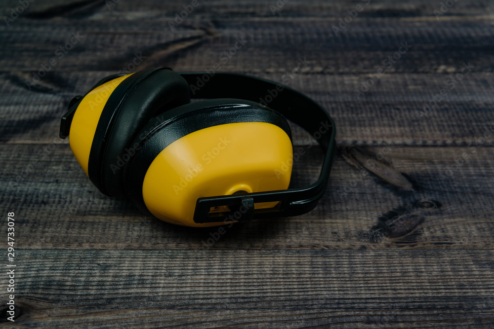 Protective ear muffs on a dark wooden table. The concept of construction, taking care of safety during work. Ear protection against noise.