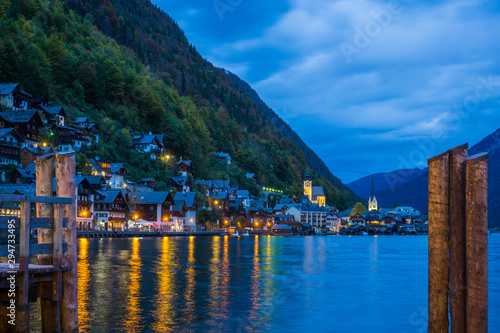 Sunset time at the famous village of Hallstatt capturing the iconic houses and church with a reflection on the lake. 