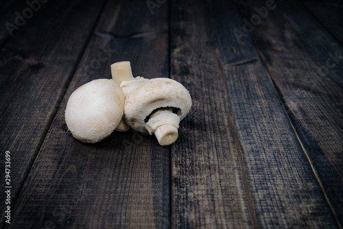 Champignons on a dark wooden table. The concept of eating mushrooms. Adding mushrooms to dishes, improving the taste of champignons dishes.