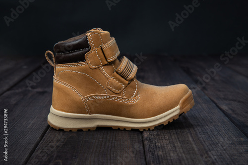 Leather, children's shoe on wooden table. The concept of upcoming cold, selling shoes. Warm, comfortable shoe for children with fur at an angle and inclination.