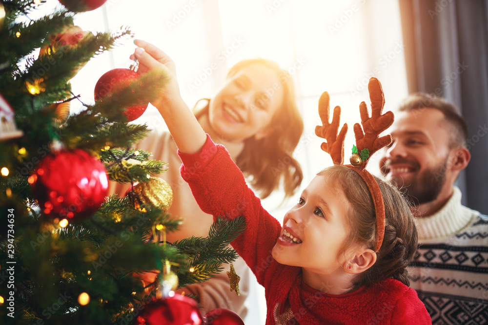 happy family mother, father and child daughter decorate Christmas tree  . - obrazy, fototapety, plakaty 