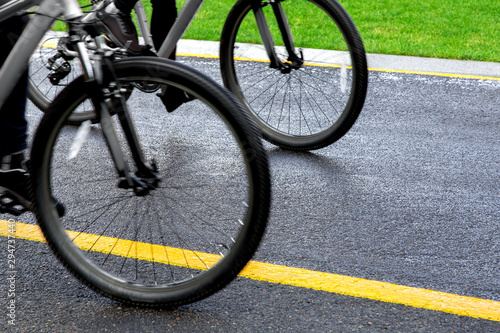 wheels of two bicycles driving along an asphalt road with yellow marking, background on the theme of cycling. close up.
