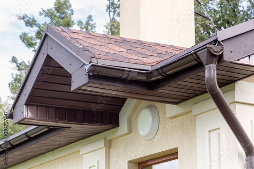 Konstfotografi brown roof visor drain gutter on a light building with a white lampshade