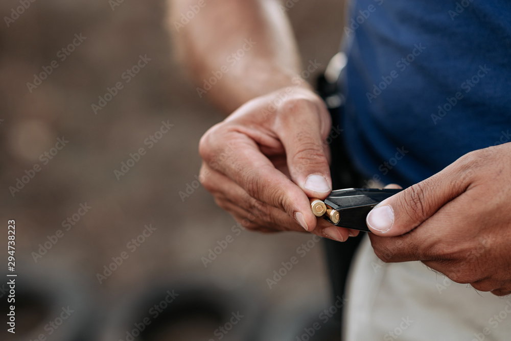 Fototapeta premium Close-up image of a bullet being put into the cartridge clip while reloading the gun.