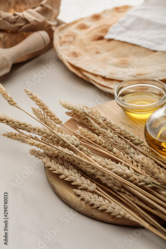 lavash bread covered with white towel near rolling pin and cutting board with spikes and oil