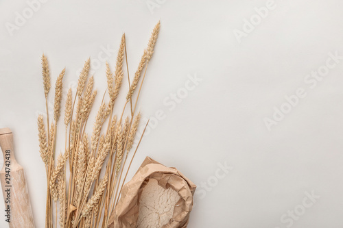 top view of wheat spikes, rolling pin and flour package isolated on white photo