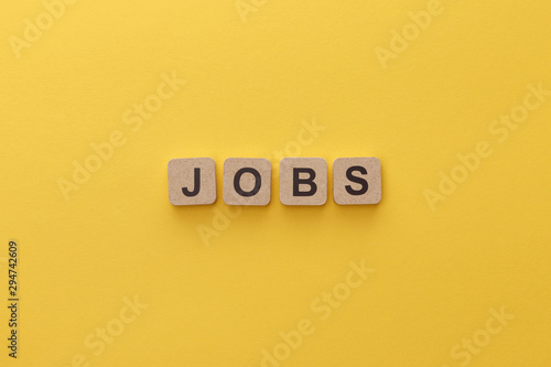 top view of cardboard squares with jobs lettering on yellow background photo