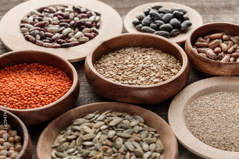 wooden bowls with raw oatmeal, red lentil, various beans, quinoa and pumpkin seeds