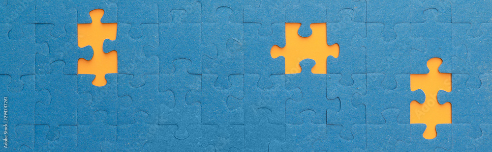 panoramic shot of blue jigsaw puzzle with yellow gaps panoramic shot of blue jigsaw puzzle with yellow gaps