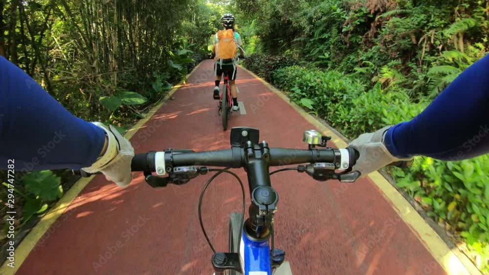 Two friends riding bike on bicycle path in park Two friends riding bike on bicycle path in park