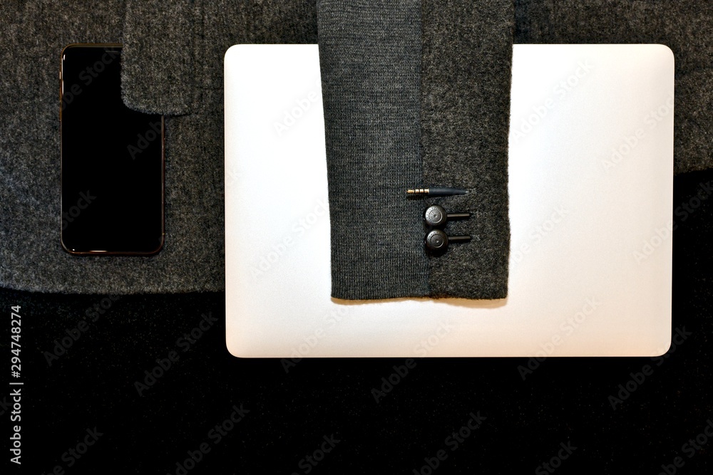 Laptop and smartphone on a gray jacket. Laptop and smartphone on a gray jacket.