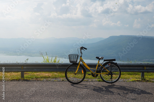 Active life / A young man with a bike enjoys the sky view on top of mountain. A young man is cycling into the sunset in the park. Young man relax with beautiful landscape image and Bicycle.