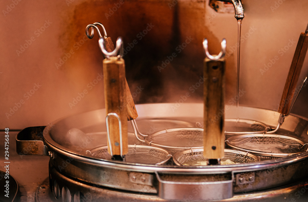 Obraz premium Hot boiling Ramen pot with noodle strainers and steam. Selective focus