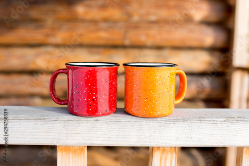 Two coffee mugs on the porch of a wooden house. Autumn and winter season.