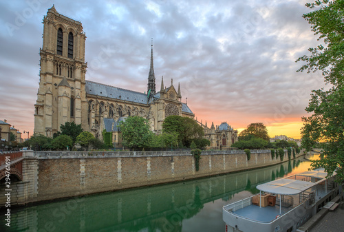 Notre Dame Cathedral in Paris France just before sunrise. Photo shows the banks of the Seine river in the foreground.