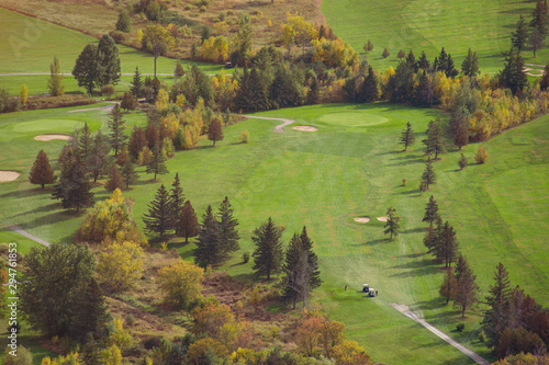 Golf course seen from above during autumn, with pine trees and other trees turning red and orange. Quebec, Canada